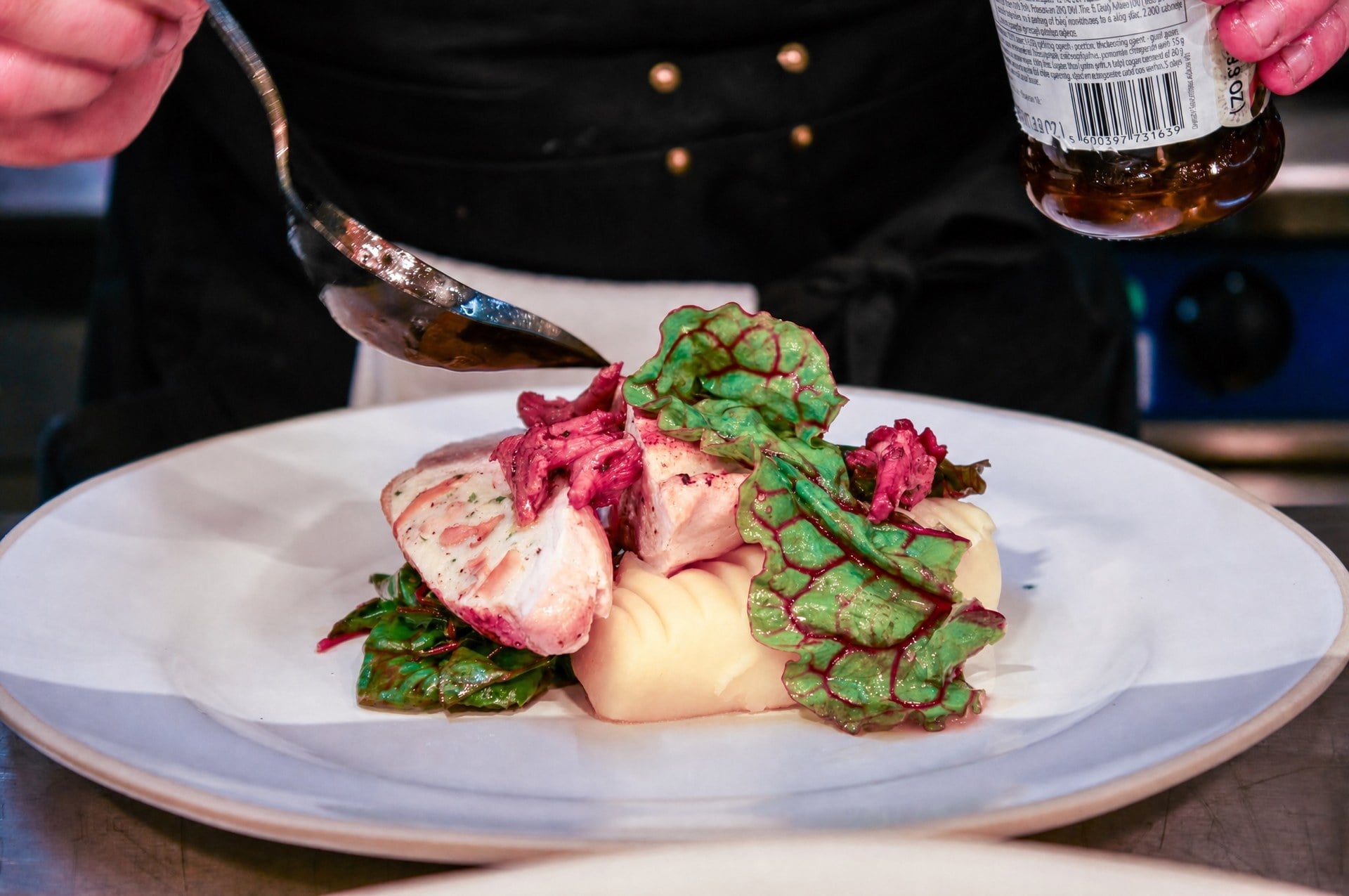 A dish being finished with sauce in the Latimers kitchen
